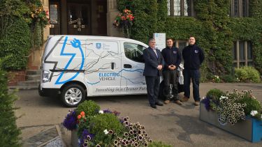 Members of the transport services team stood in front of an electric vehicle parked outside Firth Court