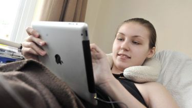 A girl laid in bed with an ipad