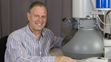 Professor Mark Rainforth sat next to imaging equipment in his lab
