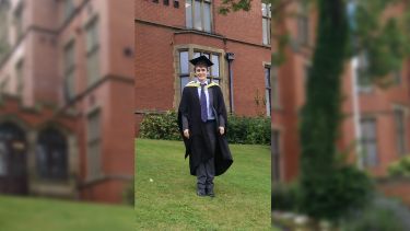 Calvin in graduation robes, in front of Firth Court