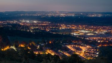 Dusk or night time landscape over small british town, showing street lamps, and denser populations in the distance