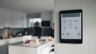 Thermostat app on digital tablet mounted over white wall at home 