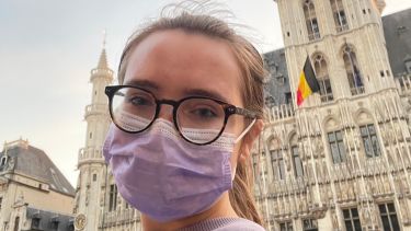 student in Brussels' main square with Belgian flag in the background