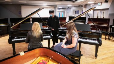 Students watching each other play the piano