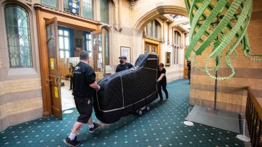 piano being wheeled down corridor in Firth Court