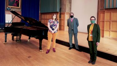 Staff standing by piano