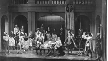 Black and white theatre production. Cast on stage
