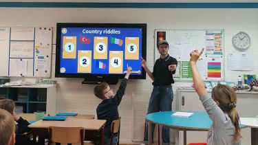 student teacher in front of classroom with children sticking up their fingers