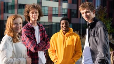 Four students standing in the sunshine