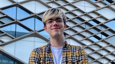 A student standing in front of the Diamond Building