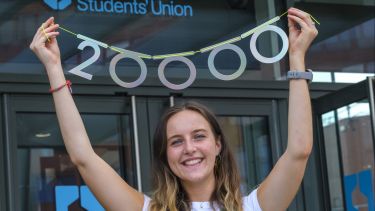 Evie Croxford, SU President 21-22, holds the number 20,000