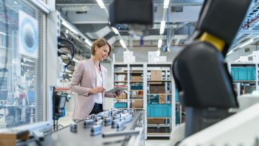 An engineer looking at a tablet next to a production line inside a factory