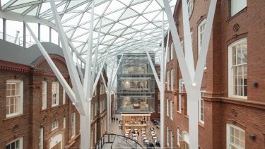 The inside of our Engineering Heartspace, two brick buildings enclosed by a glass-topped structure housing a cafe