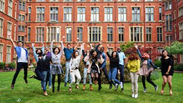 International students jump for joy on the grass outside Firth Court