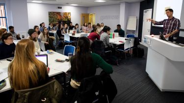 A male academic member of staff teaches a class of students