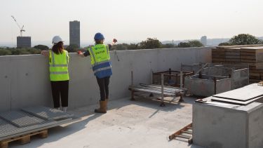 Karen Ball and Karl Brown from HLM Architects look over campus from the Social Sciences building roof
