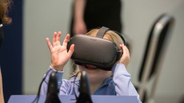 A little girl wearing a VR headset at the Pop-Up University