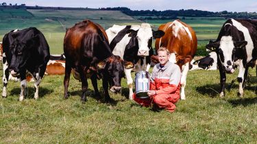 Eddie Andrew, Director of Our Cow Molly, holding a milk churn next to some cows