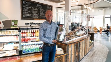 Peter Anstess, Head of Retail at the University of Sheffield, holding a milk churn in a University cafe