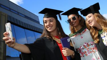 Three students at graduation having a selfie