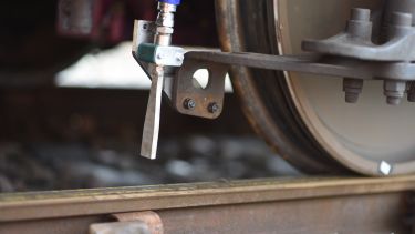 A close up of the cleaning system next to the train wheel and pointing towards the track