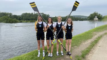 Four members of the Women's Rowing squad with their new blades, on the bank of the course