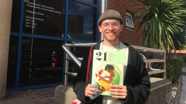 Student showing magazine with big smile