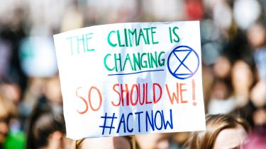 Global climate change strike: in the crowd an attendee holds a sign saying "The climate is changing, so should we. Act now". 