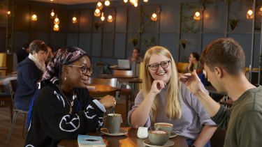 Three Sheffield students drinking coffee in Coffee Revolution