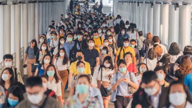 A crowd of people walking with masks on