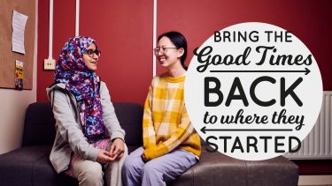 two female students sat on a sofa talking with logo that reads bring the good times back to where they started