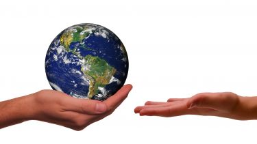 A hand holding the globe handing it over to an empty hand