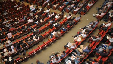 A large number of people seated in a large auditorium.