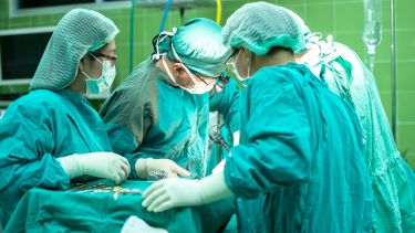 4 surgeons in green medical outfits working in a hospital