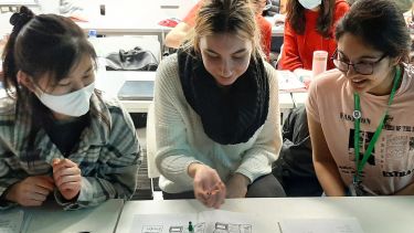 Three students playing a language games with a dice