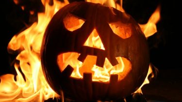 A carved pumkin in sillhouette against flames