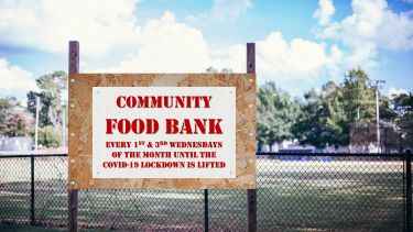 A white sign with red text reading 'Community Food Bank. Every 1st and 3rd Wednesdays of the month until the Covid-19 lockdown is lifted'