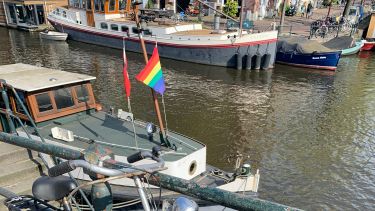 boats in canal in Amsterdam with a rainbow flag