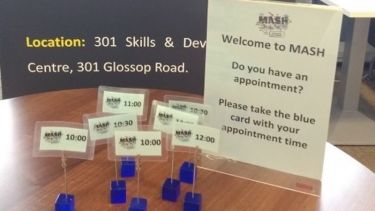 Blue appointment cubes on a wooden table with MASH signs in the background