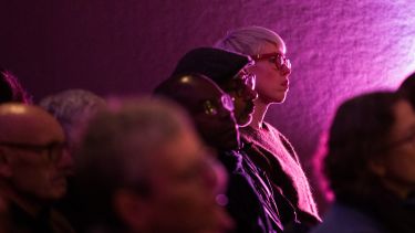 People sitting in an audience, bathed in purple light