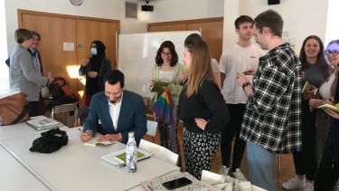 Author is signing book with group of students around him