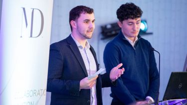 Economics students Will and Ralph at a podium speaking about the Twikker Fund.