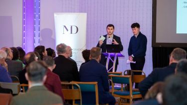 Economics students Will and Ralph speaking about the Twikker Fund on stage at an event