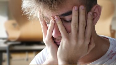 A man with his eyes closed and his hands over his face.