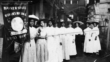 A group of Black suffragettes holding up a banner