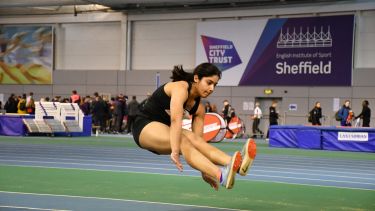 Student jumping as part of varsity long jump competition