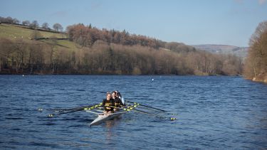 Female student rowers on river in Peak District