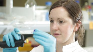 Woman looking closely at test tube in lab