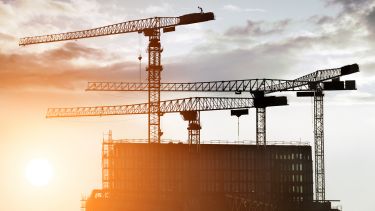 Cranes over a building at dusk