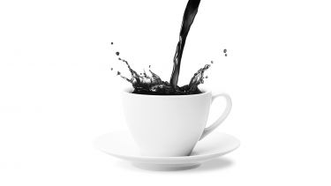 Tea being poured into a white cup and saucer
